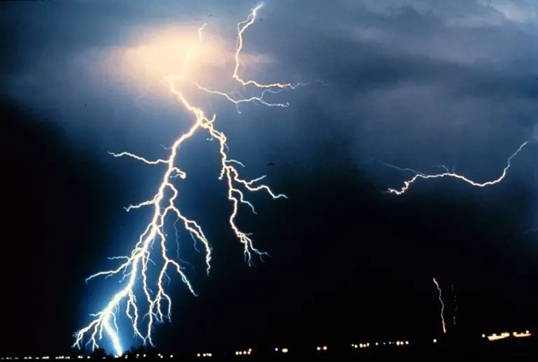 A bright, branching lightning bolt striking from a thunderstorm